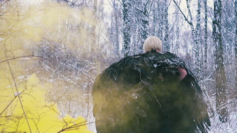 woman in black phoenix costume walks through mist in forest