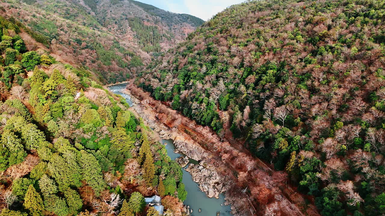 Flying over the narrow river wiggling among the rocks. Picturesque mountains in Kyoto, Japan. Aerial view.
