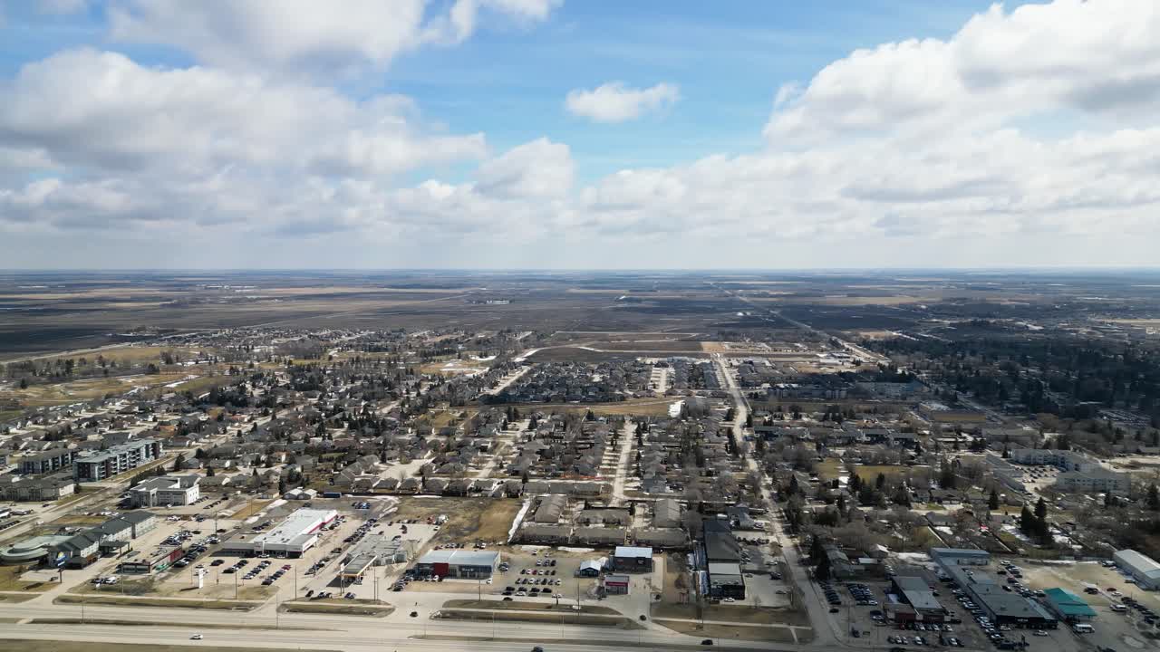 Timelapse aerial drone shot panning across the small Canadian town of Steinbach, Manitoba with a wide view of the entire community during daytime