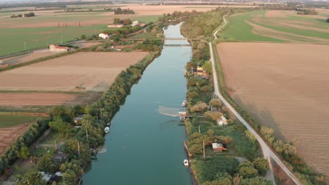 Aerial-shot-of-fishing-huts-on-river-with-typical-italian-fishing-machine,-called-"trabucco",Lido-di-Dante,-fiumi-uniti-Ravenna-near-Comacchio-valley