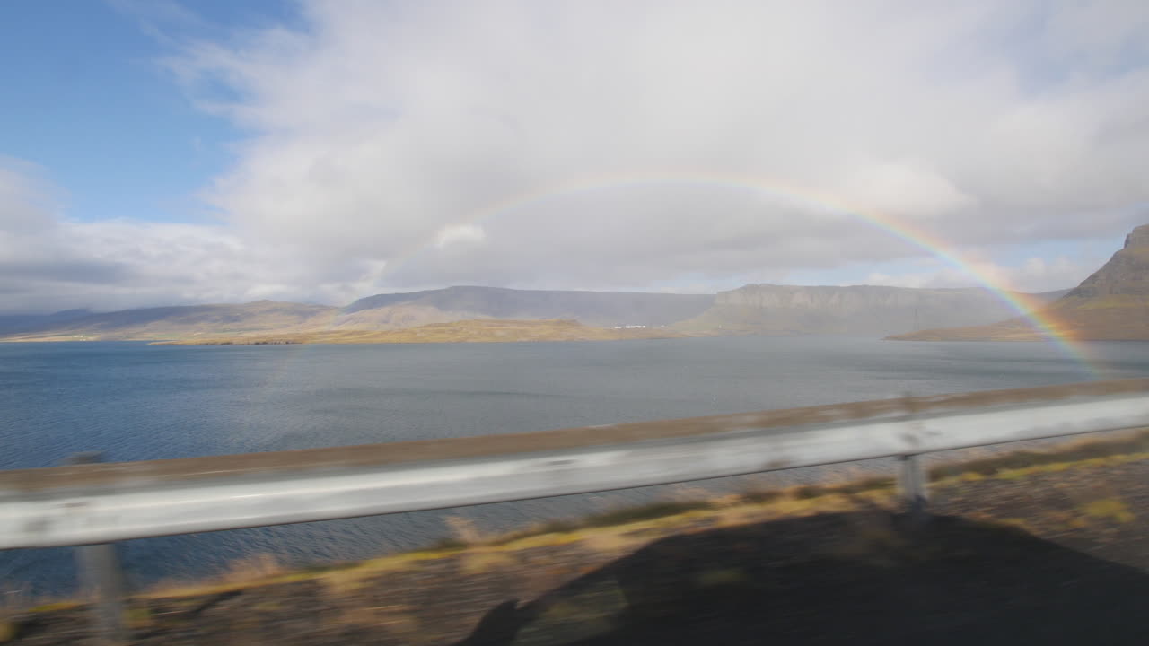 rainbow along a coastal road in Iceland. View from a car