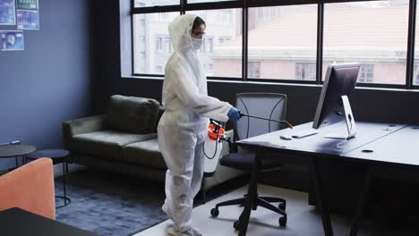 limpiador con ropa de protección desinfectando el espacio de oficina moderno