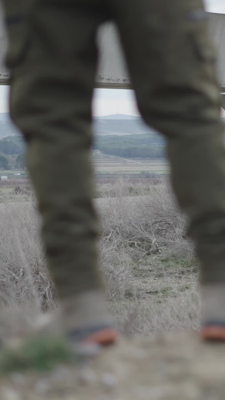 Man in a field under a bridge
