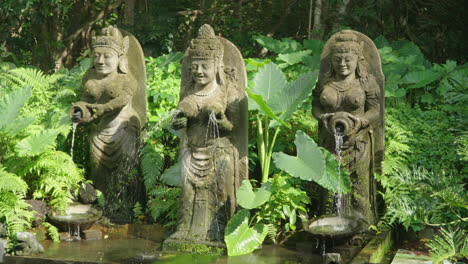 Three-Stony-Women-Statues-Fountain-in-Entrance-of-Sacred-Monkey-Forest-Sanctuary-Bali-Indonesia-With-Jungle-in-the-Background---panning-shot