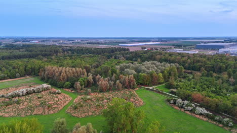 green fields and trees. aerial view of a green landscape with diverse trees, fields, and distant industrial structures