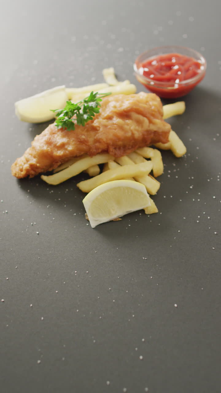 video vertical de pescado frito casero fresco y papas fritas en fondo gris