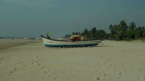 traditional fishing boat on sandy beach with tropical palms in the background, clear blue sky