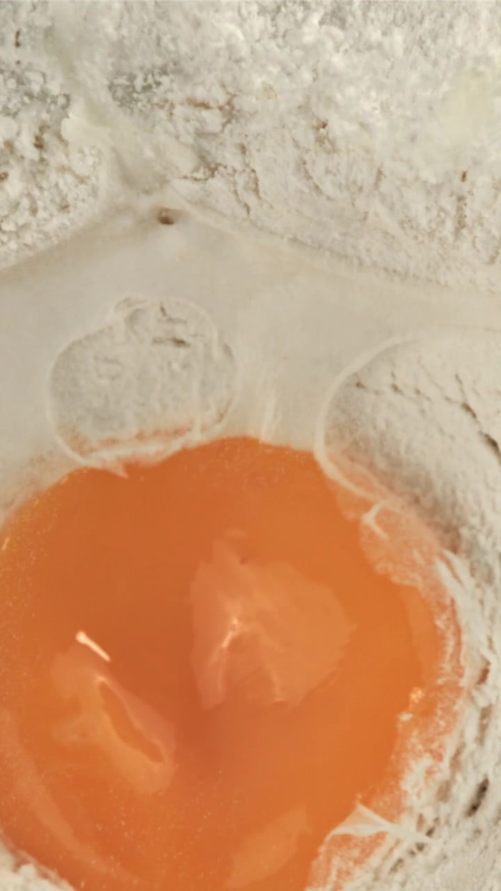 Close-up of Egg Yolk and Water Mixing with Flour