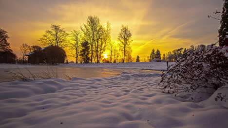 Zeitrafferaufnahme-Eines-Holzhauses,-Umgeben-Von-Weißem-Schnee-Mit-Zugefrorenem-See-Im-Vordergrund-Bei-Sonnenaufgang