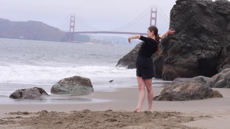 woman dancing barefoot, alone on golden gate bridge beach in san francisco