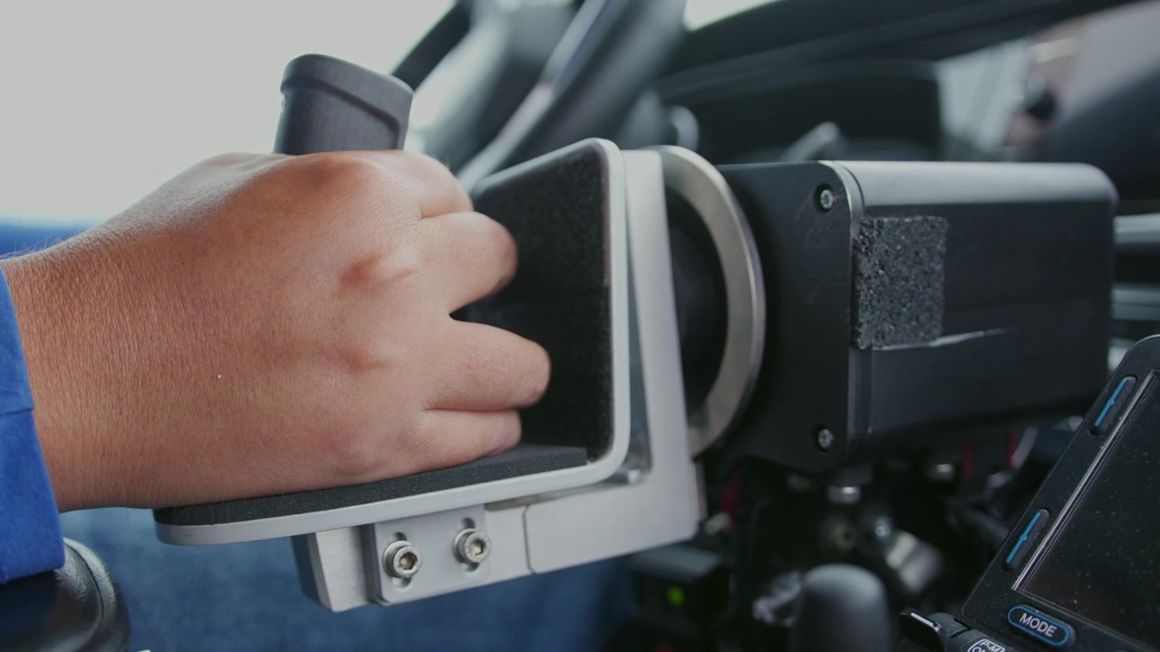 Primer plano de controles manuales adaptativos utilizados por un usuario de silla de ruedas motorizada conduciendo una furgoneta adaptada