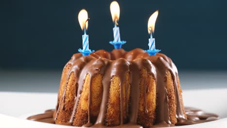 burning blue birthday candles on marble cake with chocolate nougat icing