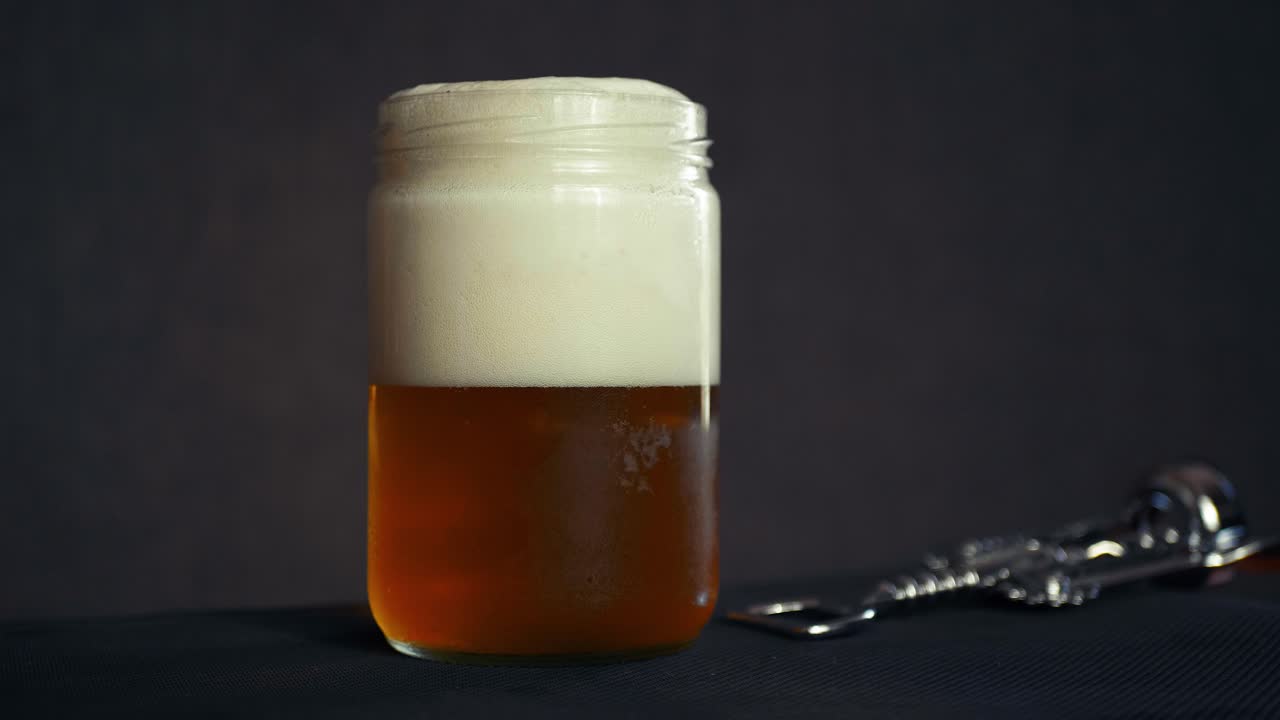 Pouring beer, foam alcoholic beverage drink in artisanal glass jar pub style