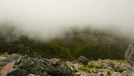 timelapse - mist flowing into valley, shot from rocky vantage point on mountain with hiking trails in background