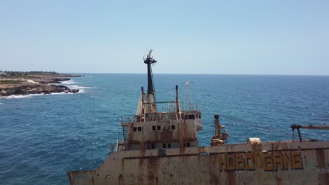 aerial drone shot revealing an old stranded ship next to the coast in cyprus