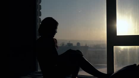 graceful girl looks at sunset on rest place near window