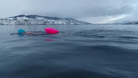 mujer nadando en un lago en suiza en invierno