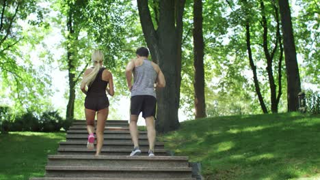 running couple climbing stairs at morning run in summer park