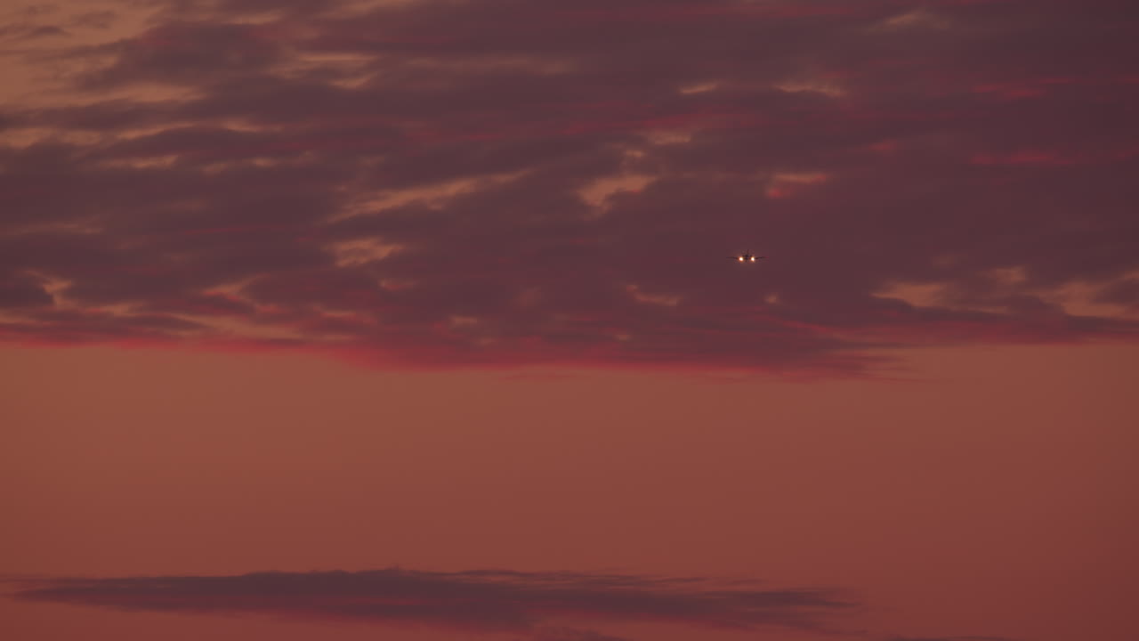Airplane Flying Through Sunset Clouds