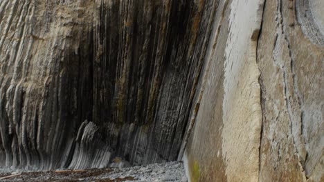 Tilt-down-along-exposed-rock-strata-layers-of-itzurun-beach,-geologic-formation-in-spain