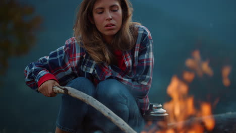 closeup tired traveler relax by dusk bonfire. thoughtful girl spend holiday.