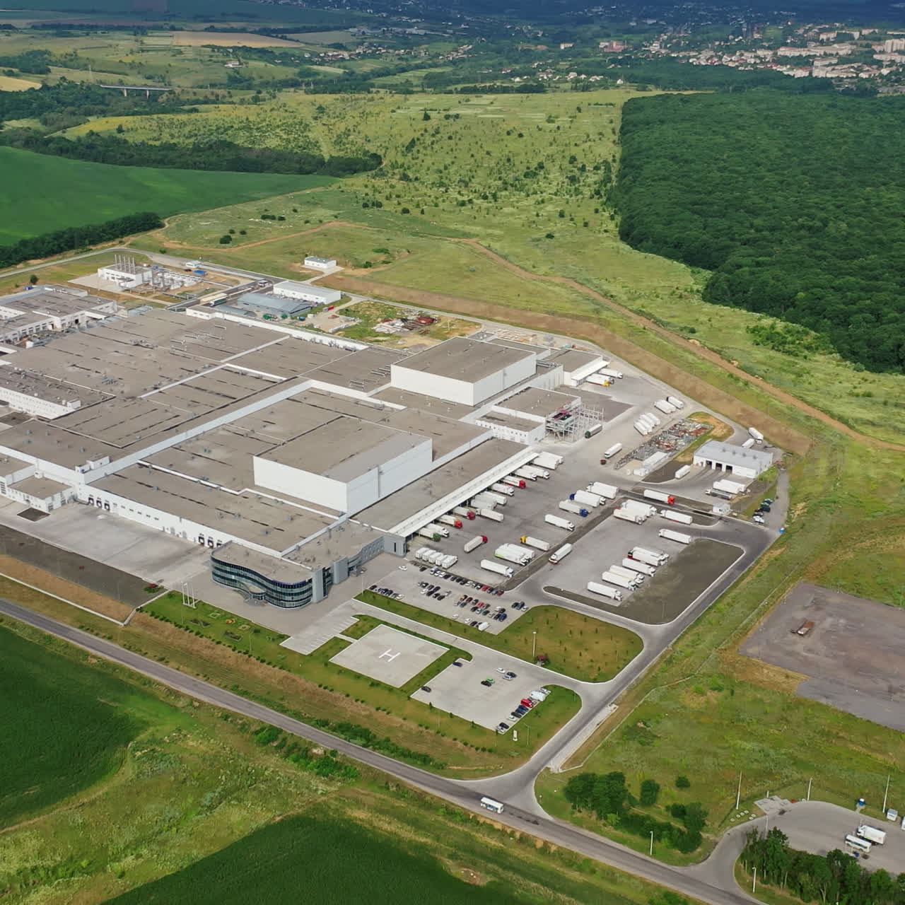 Beautiful view of natural landscape and huge industrial plant. Top view on roofing of manufacturing complex in the countryside. Slow motion.