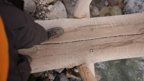 person walking across a wooden bridge over a stream