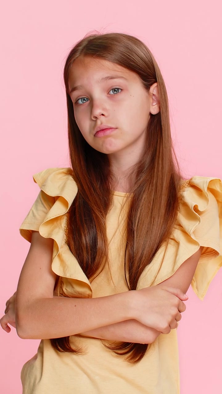 Bambina con espressione seria che fa il gesto di 'ti tengo d'occhio' con le dita puntate verso gli occhi