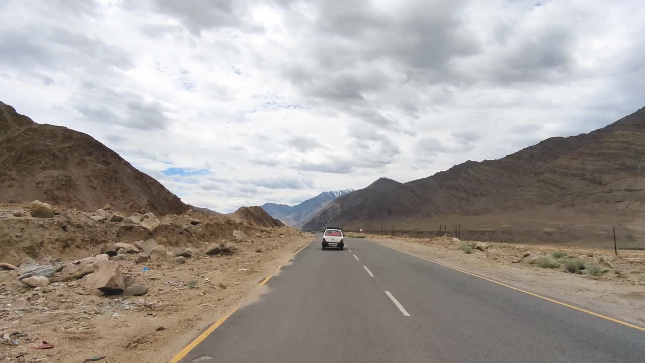 un coche viajando por una carretera del himalaya a través de las montañas de ladakh india