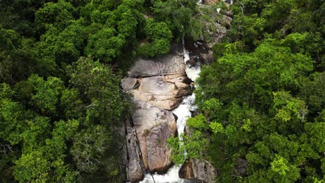 Drone-shot-of-water-flowing-in-the-lush-green-environment-of-Than-Sadet-waterfall-Koh-Phangan,-Thailand