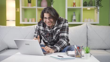 hombre alegre trabajando en una computadora portátil en casa, mirando.