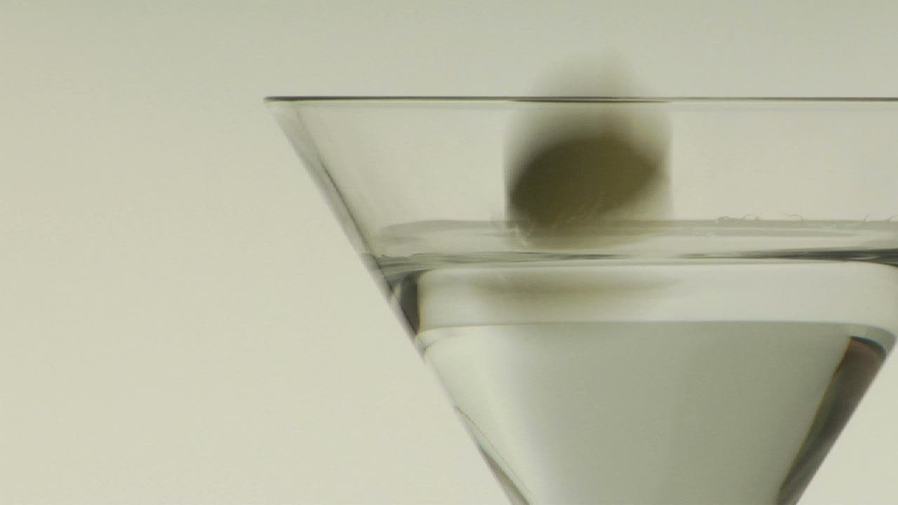 una aceituna verde se deja caer en un martini 1