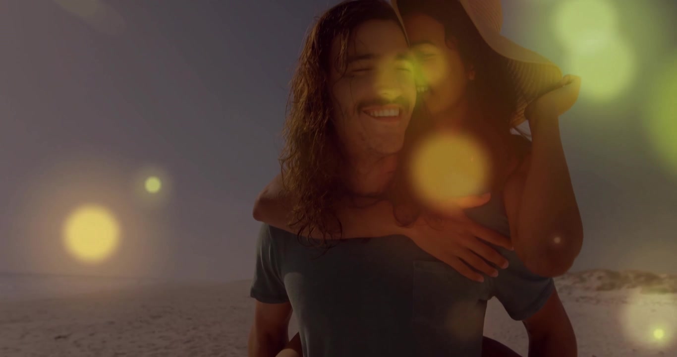 Plano médio de viagem revelando um casal andando de cavalinho na praia, compartilhando amor através de bokeh dourado