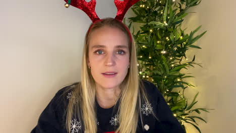 young woman on christmas video call attempting to guess word during a charades game