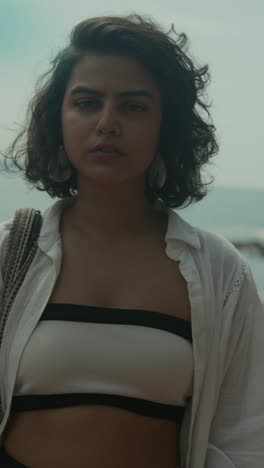 young woman on beach, relaxed vibe, wearing beachwear, casual open shirt, sunny mood