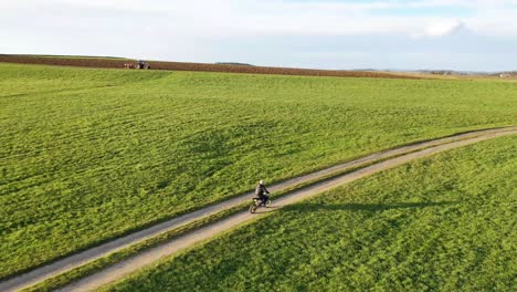 person riding a motorcycle on a dirt road through a green field