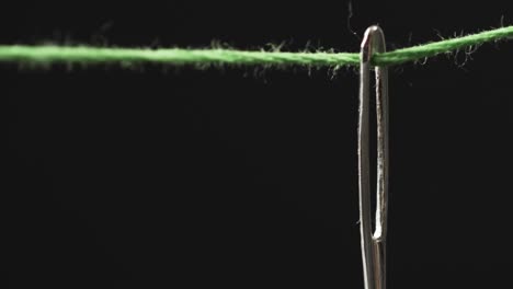 Video-of-micro-of-green-thread-going-through-needle-with-copy-space-on-black-background