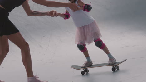 attractive woman teaching teenage daughter skateboarding