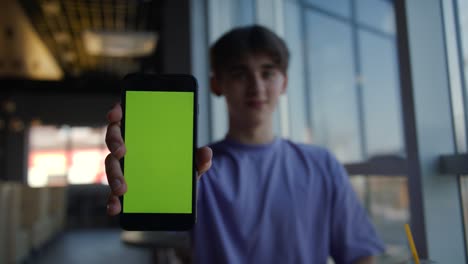 front view smart phone display for game or surfing or app. green screen vertical mockup keying for tracking presentation advertising video content or news blog. man closeup holding phone chroma key