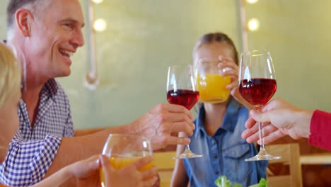 Familie-Stößt-Im-Restaurant-4K-Auf-Ein-Glas-Wein-Und-Saft-Zu