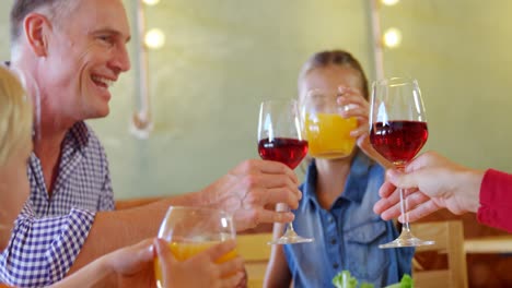 family toasting glass of wine and juice in restaurant 4k