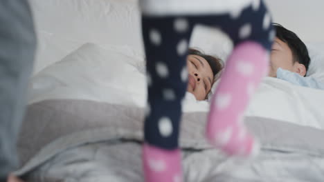 happy asian children jumping on bed little girl and her brother waking up mother and father enjoying playful morning with kids on weekend at home 4k footage