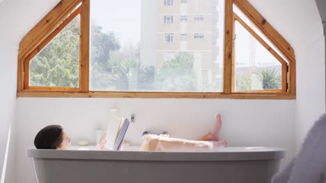 woman reading a book while relaxing in a bathtub