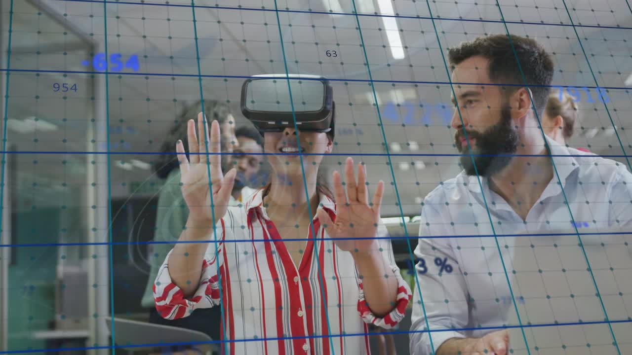 woman donning VR headset and gesturing, animating blue tech grid while colleague guiding via laptop