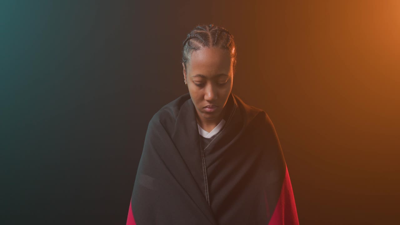 Afroamerikansk kvinde der løfter flag på kunstgræs iført fodboldstøvler, mens kameraet vipper opad for at afsløre ansigtet