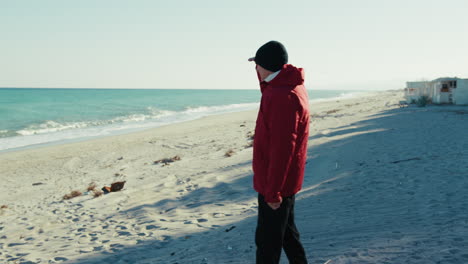 elderly man reaches the winter sea and looks around shielding from the sun