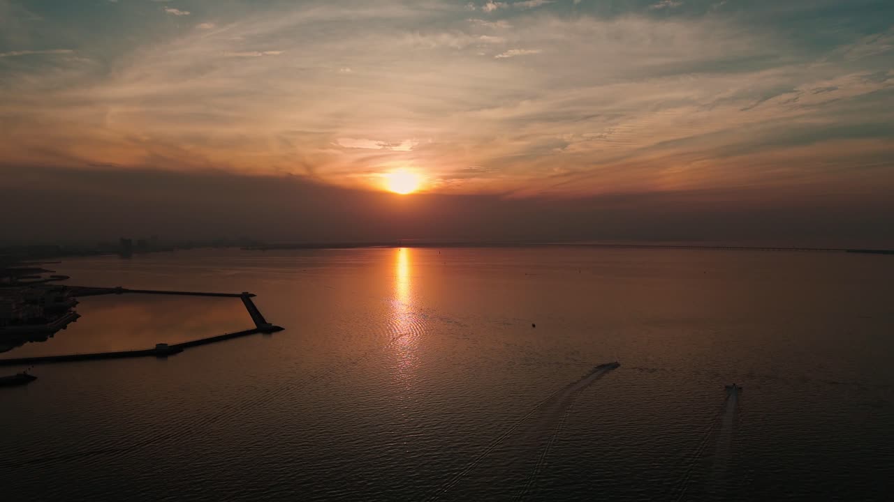 Breathtaking 4K aerial shot of a golden sunset over the calm Arabian Gulf, with two speedboats gliding across the water near Kuwait’s coast. Perfect for cinematic and travel content.