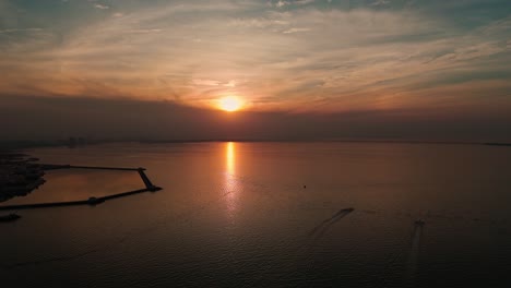 breathtaking 4k aerial shot of a golden sunset over the calm arabian gulf, with two speedboats gliding across the water near kuwait’s coast. perfect for cinematic and travel content.