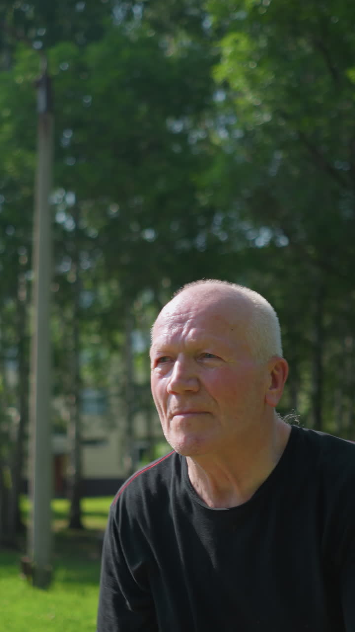 검은 셔츠를 입은 노인이 공을 잡고 던지는 클로즈업, 집중된 표정으로