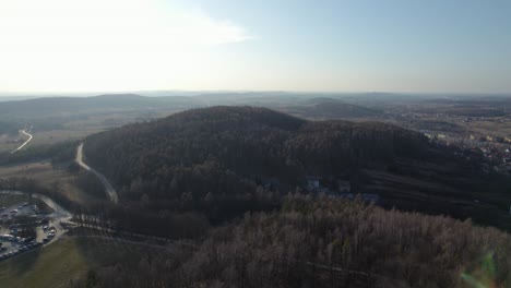 A-rearward-aerial-drone-shot-of-the-mountain-landscapes-in-Poland-while-revealing-the-Chęciny-Royal-Castle-lengthwise